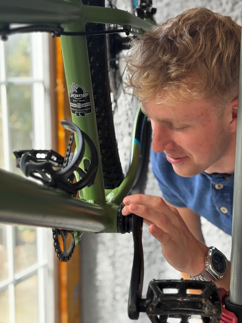 Callum looking closely at a mountain bike drivetrain in the workshop.