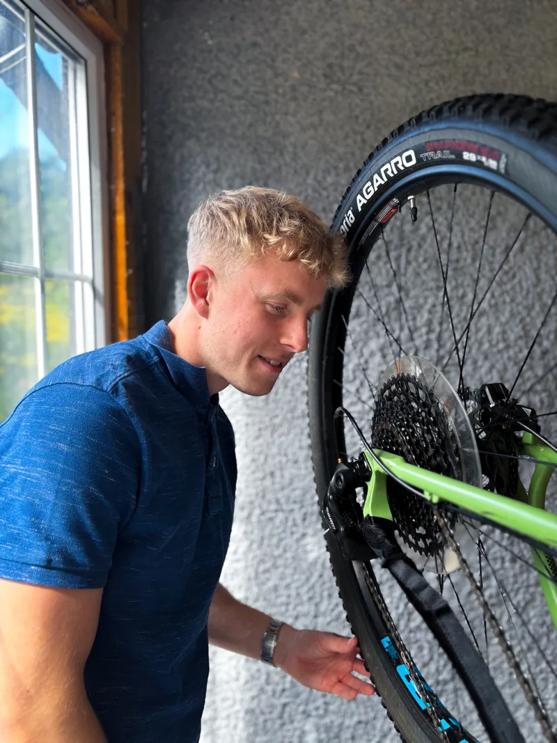 Callum working beside a mountain bike wheel in the workshop.