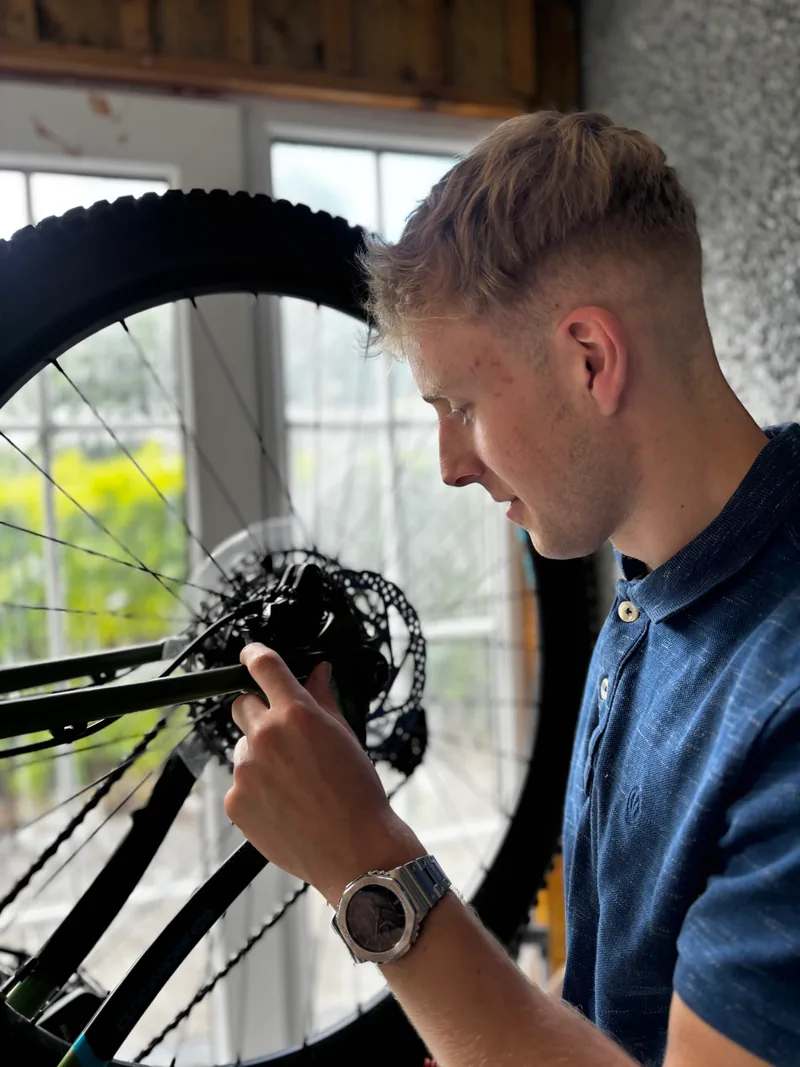 Callum inspecting a mountain bike disc brake in the Canny Cycles workshop.